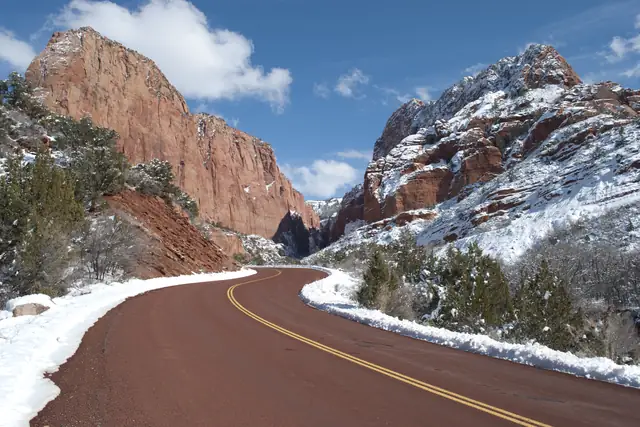 The Kolob Canyons Road curving between snow-dusted red cliffs after a winter storm, Zion National Park.